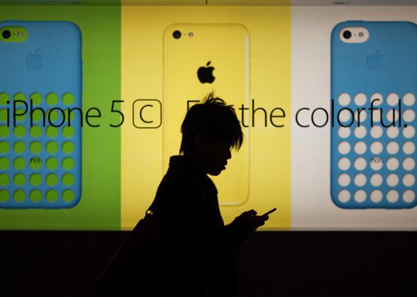 A man uses his phone as he walks past an Apple Store on Dec. 25, 2013.